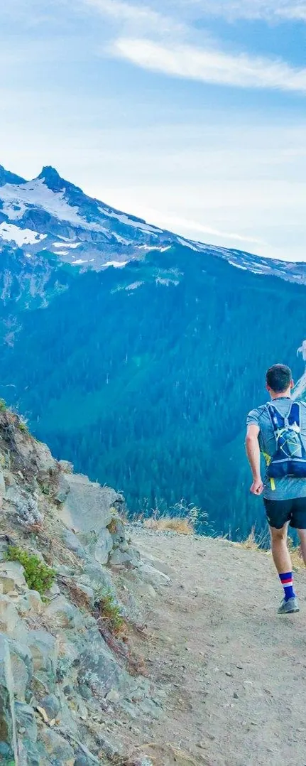 Runner seen from behind on a ridge trail, mountains beyond